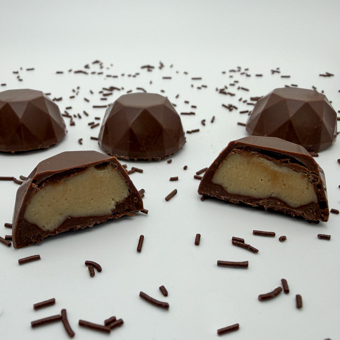 Chocolate Asscher Truffles with a creamy brown sugar center on a white surface with chocolate sprinkles.