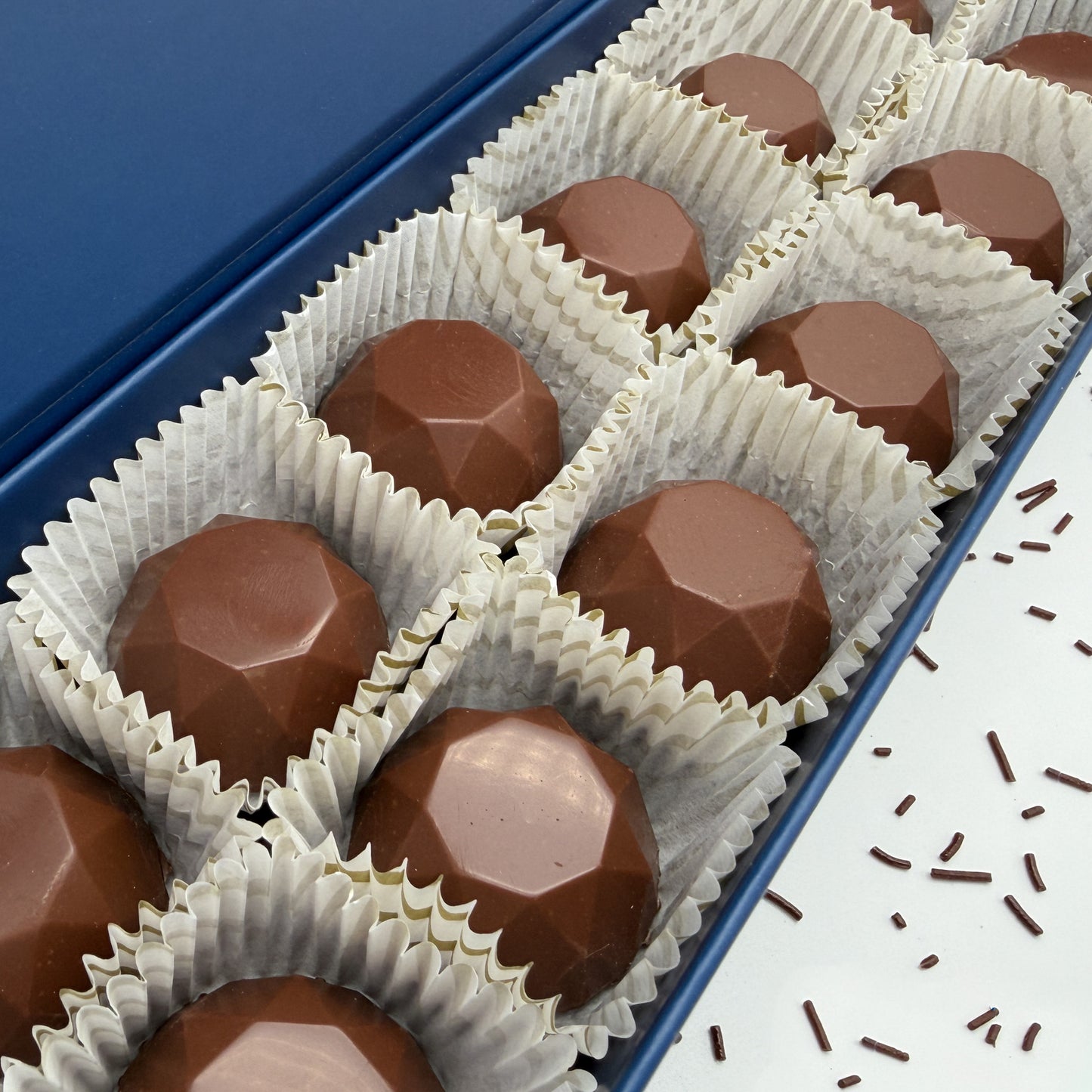 Chocolate Asschers in a blue box with white paper cups.